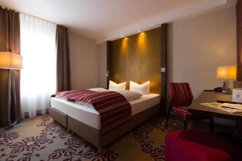 ゲルンハウゼンにあるHOTEL PARQÉO im A66のベッドとデスクが備わるホテルルームです。