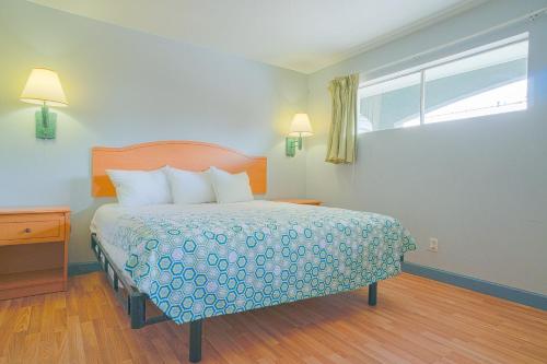 a bedroom with a bed with a blue bedspread and a window at OYO Hotel Midland in Midland