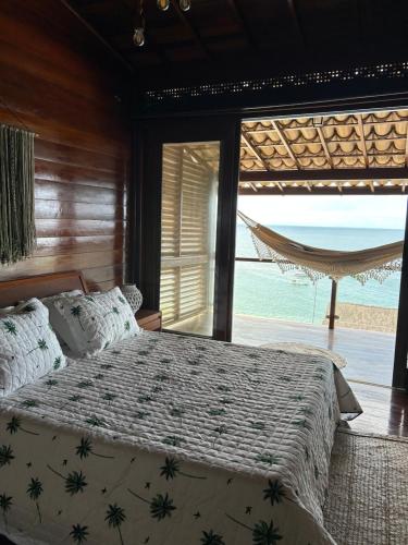 a bedroom with a bed with a view of the ocean at Aroeiraecocasa in Morro de São Paulo