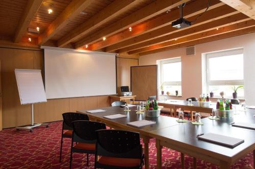a conference room with a large table and a projection screen at HOTEL PARQÉO im A66 in Gelnhausen