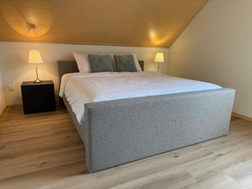 a large bed in a bedroom with a wooden floor at Villa Luna in Oudsbergen 