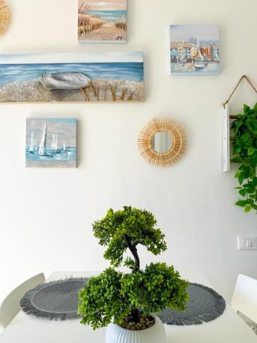 a plant in a white vase on a table with pictures at Vistamare Oltremare in San Cataldo