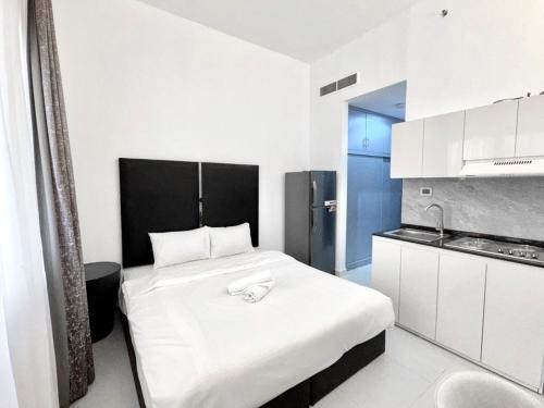 a bedroom with a white bed and a kitchen at Al Manara Classic Deluxe Studio in Dubai