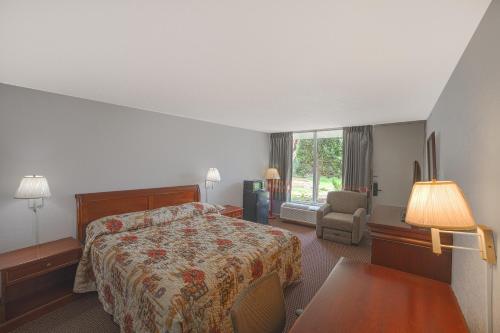 a hotel room with a bed and a chair at Masters Inn Selma Smithfield I-95 By OYO in Selma