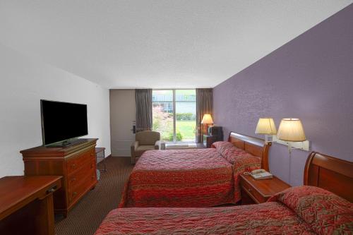 a hotel room with two beds and a flat screen tv at Masters Inn Selma Smithfield I-95 By OYO in Selma