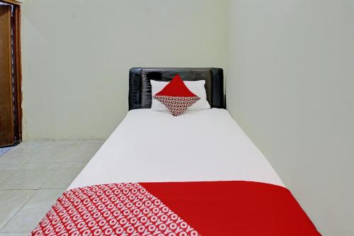 a bed with a red and white blanket on it at OYO Life 92312 A+ Cozy Rooms Syariah in Kediri