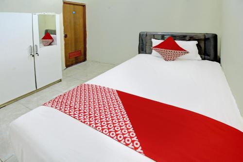 a bed with a red and white blanket on it at OYO Life 92312 A+ Cozy Rooms Syariah in Kediri