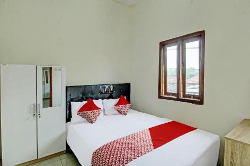 a bedroom with a bed with red and white pillows at OYO Life 92312 A+ Cozy Rooms Syariah in Kediri