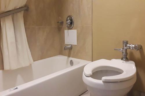 a bathroom with a white toilet and a bath tub at OYO Hotel Tallahassee Downtown in Tallahassee