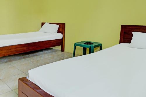 two beds in a room with a table between them at Capital O 92316 Wisma Widya Loka Pratama Near Futsal Tebing Gading in Muaradua