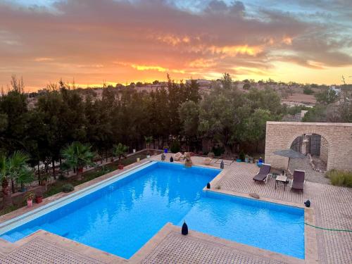 a swimming pool with a sunset in the background at QUIET OASIS Luxury Stone Villa with Panoramic Views near Essaouira in Essaouira