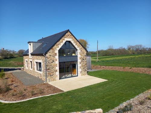 ein Steinhaus mit einem großen Fenster auf einem Rasen in der Unterkunft Maison Beniguet 6 places proche Paimpol et Tréguier in Pleumeur-Gautier