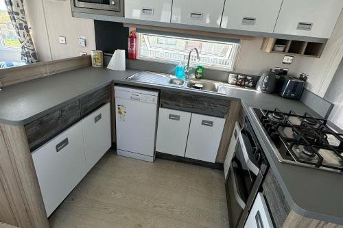 a small kitchen with a sink and a stove at Lighthouse Lodge - Peaceful & Dog Friendly in Sutton on Sea