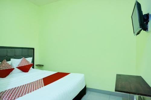 a bedroom with a bed with red pillows and a television at Hotel O Parapat Near Dermaga Ajibata Formerly Pudan Residence 2 in Parapat