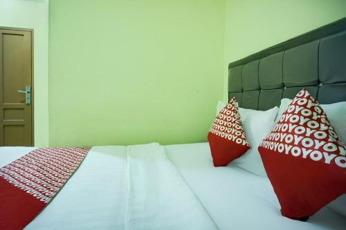 a bedroom with a bed with red and white pillows at Hotel O Parapat Near Dermaga Ajibata Formerly Pudan Residence 2 in Parapat