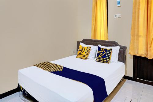 a bed with blue and yellow pillows on it at OYO Life 92353 Purnama Syariah Guest House in Blitar