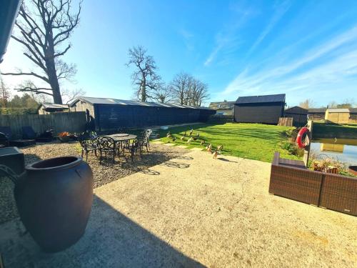 a patio with a table and chairs and a yard at Milk Barn - Rustic farm stay in Great Chart