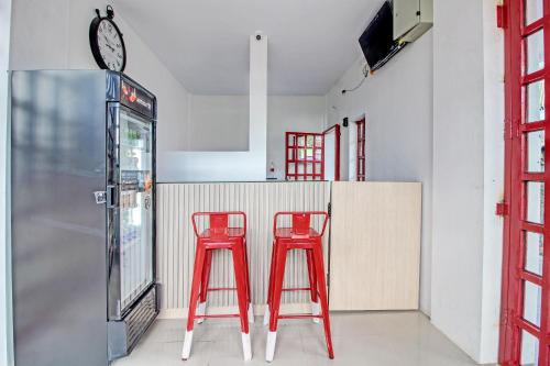 two red stools in a kitchen with a counter at Collection O 92363 Kp Inn in Yogyakarta