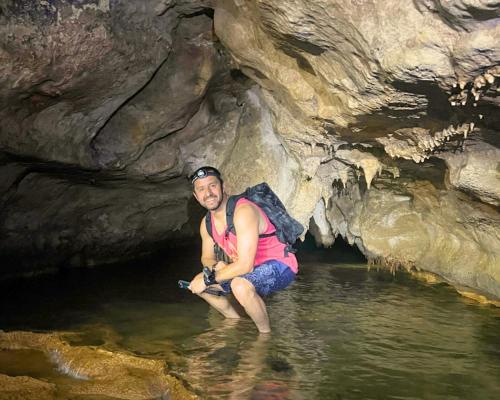 a man sitting in the water in a cave at Grutas el Encanto - Casa de la Colina - Ruta a Petén in Rio Dulce
