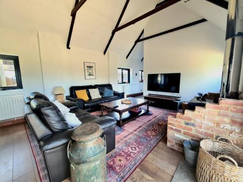 a living room with a couch and a tv at Milk Barn - Rustic farm stay in Great Chart