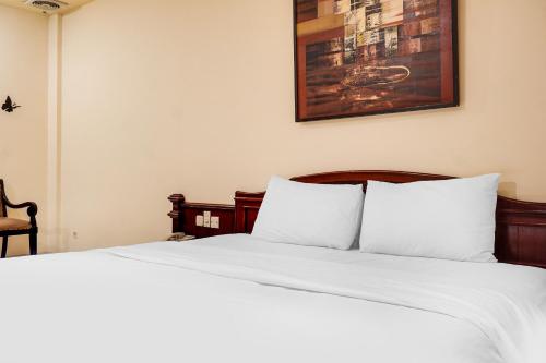 a bed with white sheets and a picture on the wall at Townhouse OAK Bi Executive in Jakarta