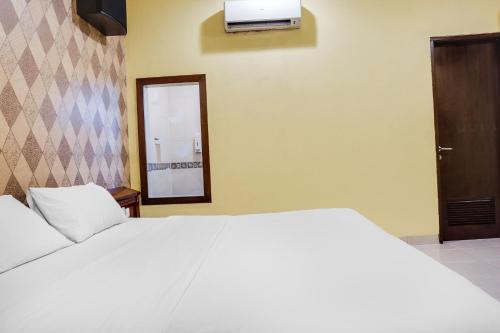 a bedroom with a white bed and a television on the wall at Townhouse OAK Bi Executive in Jakarta
