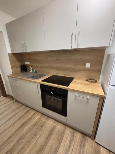 Una cocina con gabinetes blancos, un fregadero y una estufa. en KINO & Netflix apartman v srdci mesta, en Prešov