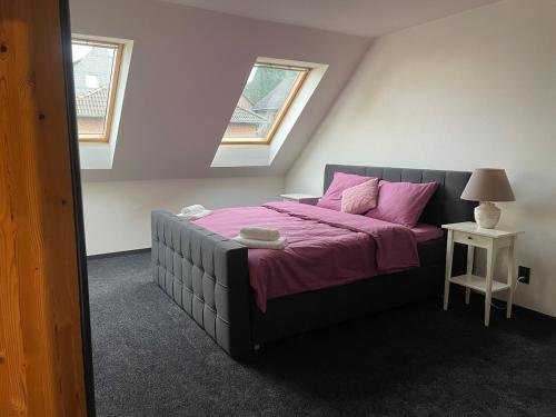 a bedroom with a large bed with pink sheets and two windows at Dhünn lake holiday house in Kürten