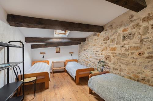 Cette chambre comprend 2 lits et un mur en pierre. dans l'établissement Gîte de La Tour, à Saint-Guilhem-le-Désert