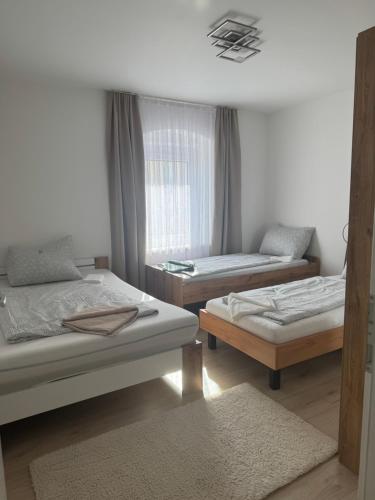 a room with three beds and a window at Wohnungen Beshi Niederthalheim in Vöcklabruck