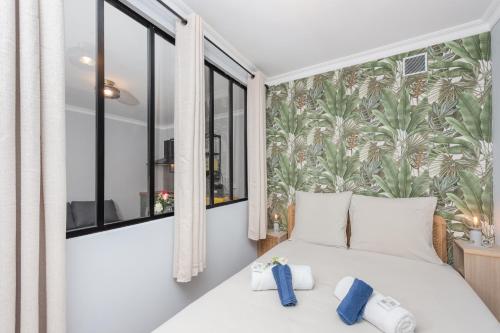 - une chambre avec un lit blanc et un papier peint tropical dans l'établissement Les tennis, à Roquebrune-Cap-Martin