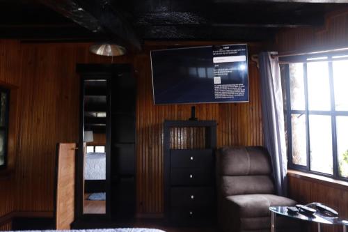 Habitación con TV, silla y espejo. en El Balcón del Aventurero, en San Cristóbal de Las Casas