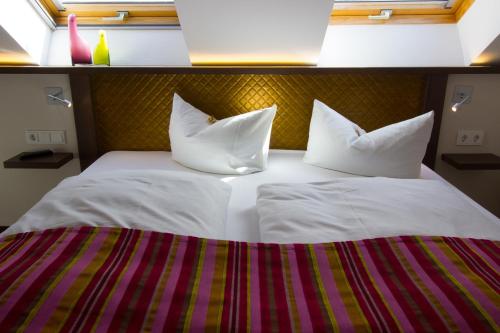 a bed with white sheets and pillows in a room at HOTEL PARQÉO im A66 in Gelnhausen