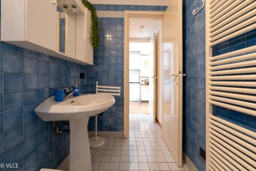 a bathroom with a white sink and blue tiles at La Casa di Anna in Varenna