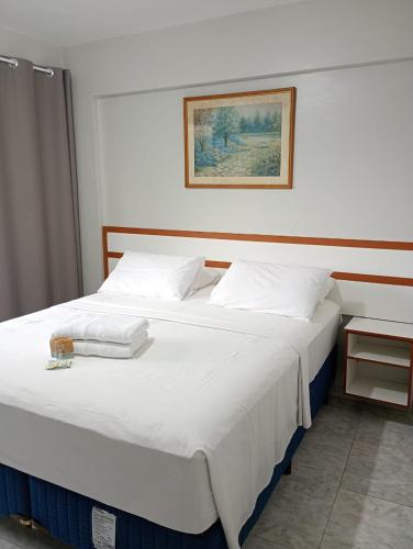 a bedroom with a large white bed with a picture on the wall at Gran hotel teatro in Manaus