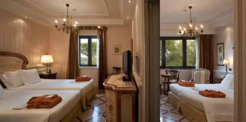 a hotel room with two beds and a television at Mercure Petriolo Siena Terme Spa Hotel in Bagni di Petriolo