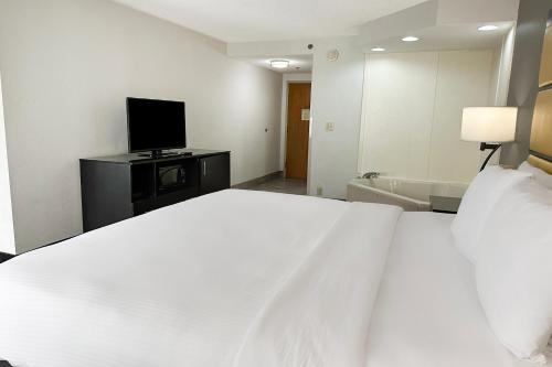 a bedroom with a white bed and a television at OYO Townhouse Jackson - Ridgeland in Jackson