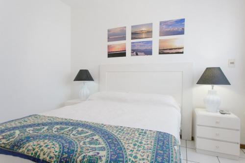 Un dormitorio blanco con una cama y dos lámparas. en Punta! Bem localizado e completo!, en Punta del Este