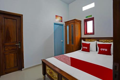 a bedroom with a bed with red pillows at Hotel O Salsabila Homestay in Pasuruan