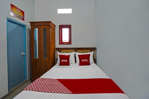 a bedroom with a bed with two red pillows at Hotel O Salsabila Homestay in Pasuruan