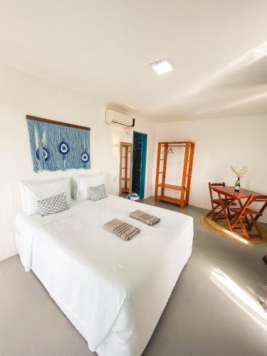 a bedroom with a white bed with two towels on it at Pousada La Grécia in Camocim