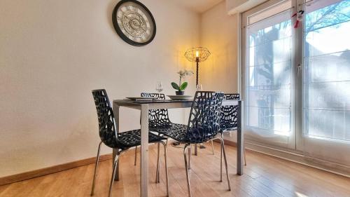 une table à manger avec des chaises et une horloge murale dans l'établissement Chez Coralie - T2, 2 pers, parking, balcon, à Colmar