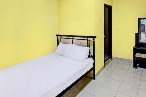 TanjungkarangにあるHotel O Kos Agi Mataram Near Masjid Hissoh Al-Fahamのベッドルーム1室(白いシーツとピアノ付)