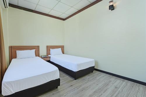 two beds in a room with white sheets and wood floors at Hotel O Pendang Lake Formerly D Jiwa in Pendang