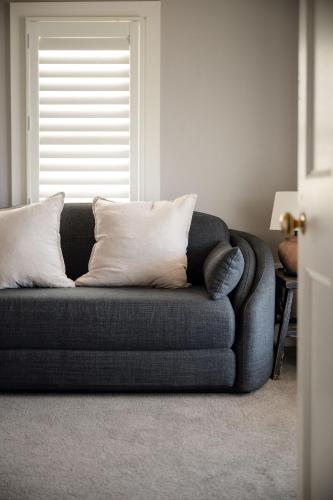 a couch with pillows in a living room with a window at Lawsons Estate on Macquarie Farm in Brewongle