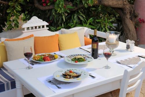 a white table with plates of food and a bottle of wine at Parthenis Hotel & Suites in Malia