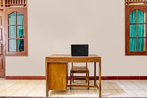 a wooden table with a chair and a laptop on it at Hotel O Puri Kasih Guest House Syariah in Solo