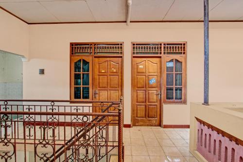 two wooden doors in a room with a staircase at Hotel O Puri Kasih Guest House Syariah in Solo