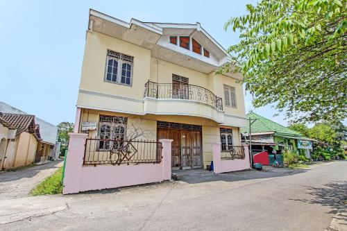 a large yellow house with a balcony on a street at Hotel O Puri Kasih Guest House Syariah in Solo