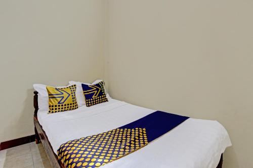 a bed with yellow and blue pillows on it at Hotel O Puri Kasih Guest House Syariah in Solo